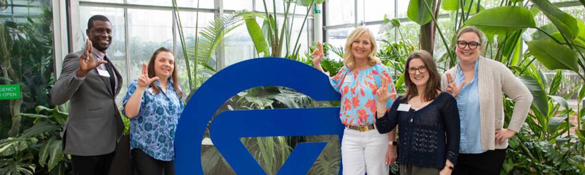 Group of faculty and staff standing together in front of circle G